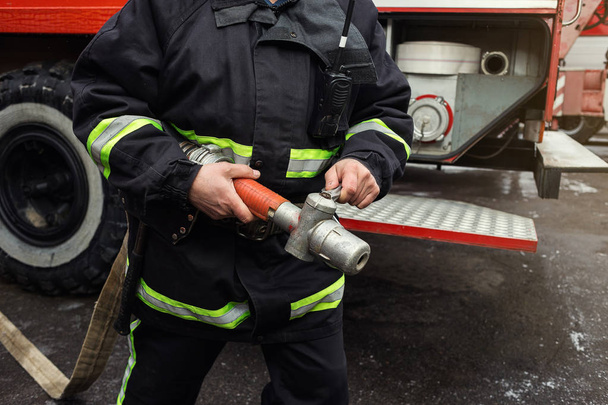 Feuerwehrmann im Einsatz in der Nähe eines Feuerwehrfahrzeugs. Notsicherung. Schutz, Rettung vor Gefahr. - Foto, Bild
