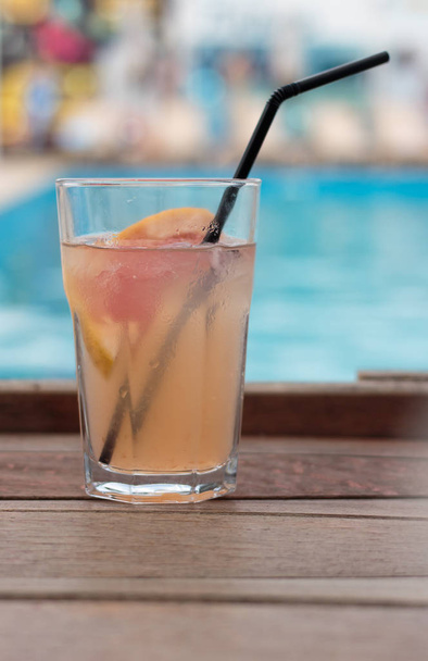 Summer drink on wood table background and swimming pool - Foto, afbeelding