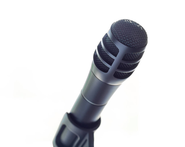 Un elegante micrófono negro en un soporte frente al espacio en blanco abierto
. - Foto, Imagen