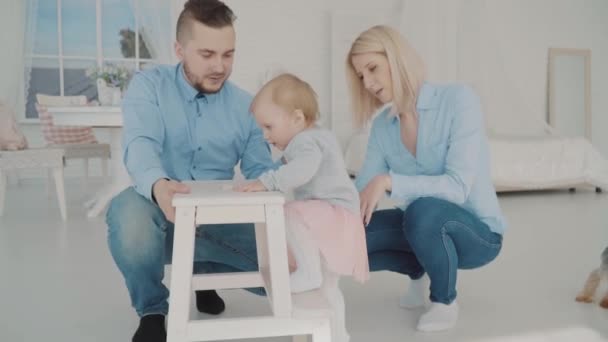 Happy family with their lovely baby near the chair. Slow motion - Imágenes, Vídeo