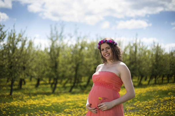 Szép terhes nő a tavaszi kert között virágzó pitypang - Fotó, kép