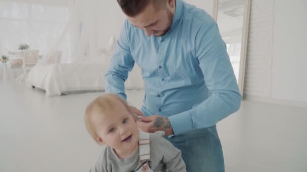 Farther dresses his beautiful daughter on knee. Happy family. Slow motion - Záběry, video