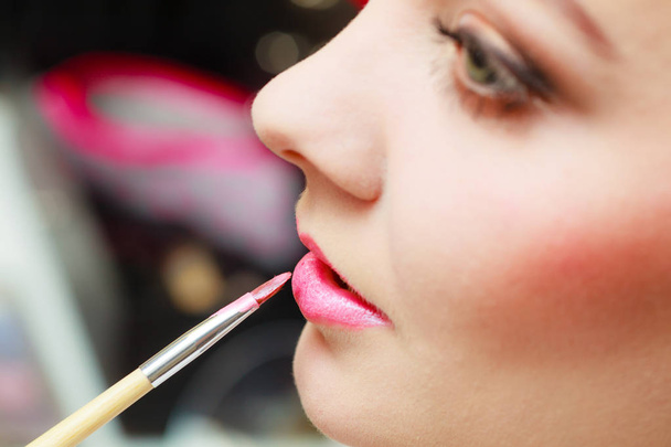 Visage concept. Close up woman getting make up on her lips. Applying lipstick with brush. - Foto, Imagen