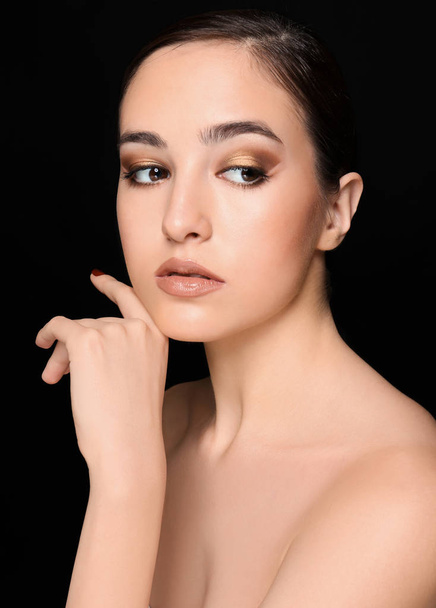 Portrait of young woman with beautiful professional makeup on black background - Fotoğraf, Görsel