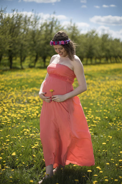Krásná těhotná žena v jarní zahradě mezi rozkvetlé pampelišky - Fotografie, Obrázek