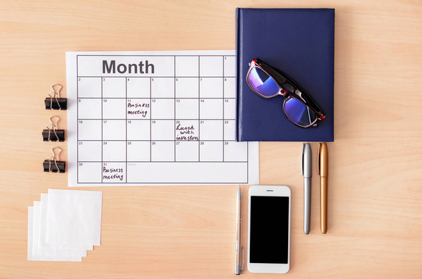 Composition with mobile phone, notebook and calendar on wooden background - Photo, Image