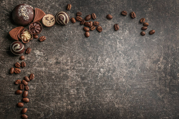 Deliciosos caramelos de chocolate con granos de café sobre fondo gris
 - Foto, imagen