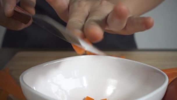 Slow motion - Close up of woman making healthy food and chopping carrot on cutting board in the kitchen. - Video