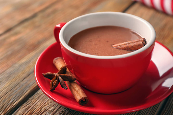 Kop lekker warme chocolademelk met kaneel op houten tafel - Foto, afbeelding