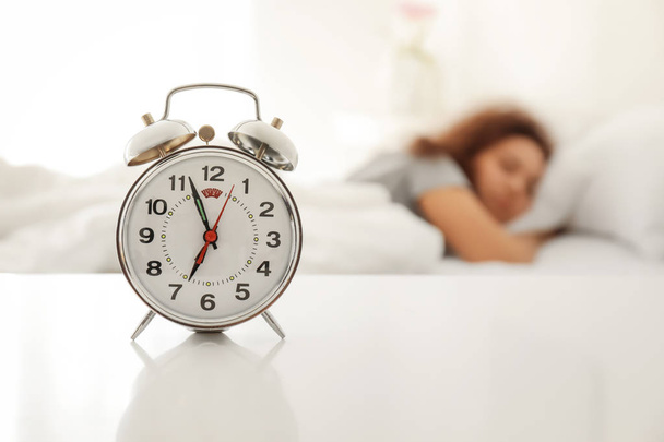 Alarm clock on table in bedroom of beautiful young woman. Morning time - Φωτογραφία, εικόνα