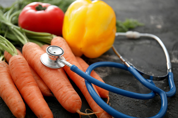 Stetoscopio con verdure su fondo grigio scuro. Concetto di cibo sano
 - Foto, immagini