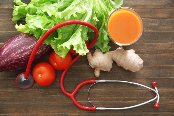 Stetoskop se zeleninou na dřevěný stůl. Zdravé jídlo koncept - Fotografie, Obrázek