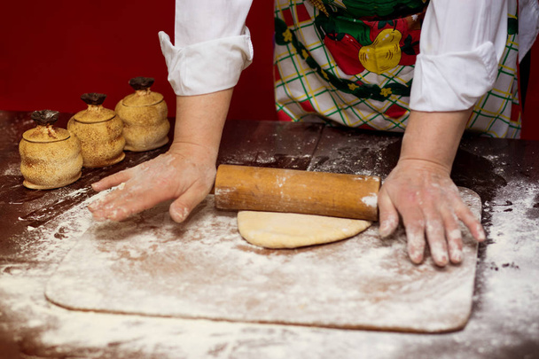 Gros plan des mains de boulangère pétrissant la pâte et faisant du pain avec un rouleau à pâtisserie. Concept de processus de cuisson
  - Photo, image