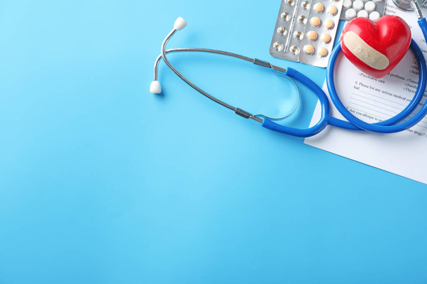 Komposition mit Stethoskop, Herz und Pillen auf farbigem Hintergrund. Gesundheitskonzept - Foto, Bild