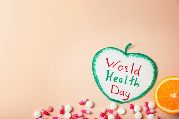 Papel en forma de manzana con frase "Día Mundial de la Salud" y pastillas sobre fondo de color
 - Foto, imagen