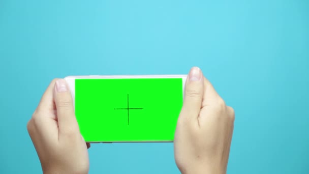 Donna che utilizza smart phone con schermo verde su sfondo blu tavolo. Mani femminili scorrono le pagine, toccando il touch screen
. - Filmati, video