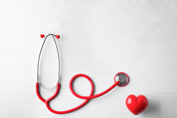Stetoskop a červené srdce na bílém pozadí dřevěná. Zdravotní péče koncept - Fotografie, Obrázek