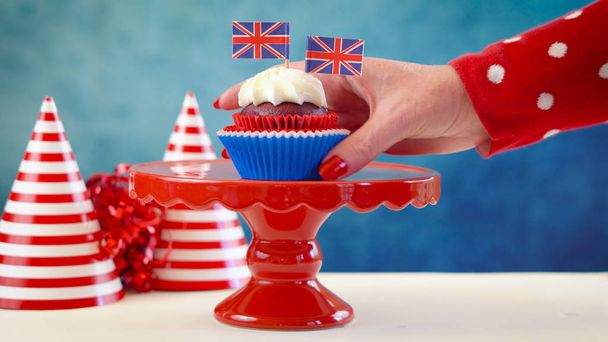 Bolinhos de tema branco e azul vermelho e stand de bolo com bandeiras Union Jack do Reino Unido
 - Foto, Imagem