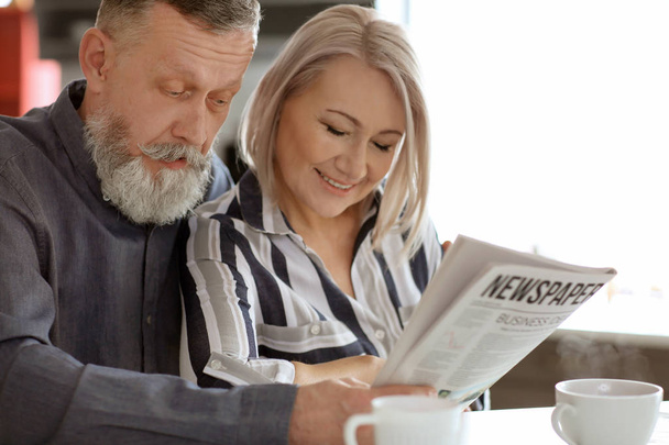 Mature couple reading newspaper at home - Foto, imagen