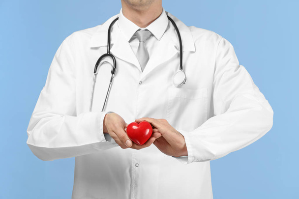 Male doctor with red heart on color background - Photo, image