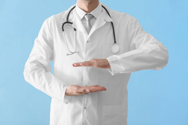 Male doctor holding something on color background - Photo, Image