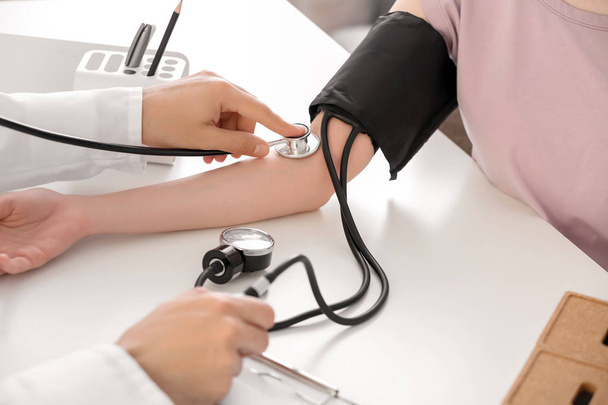 男性医師の病院で若い女性の血圧測定 - 写真・画像