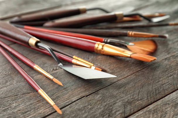 Ножи для палитры с кисточками на деревянном столе
 - Фото, изображение