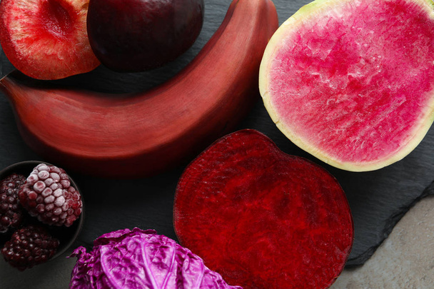 Фиолетовые и красные овощи с фруктами и ягодами на столе, крупным планом
 - Фото, изображение