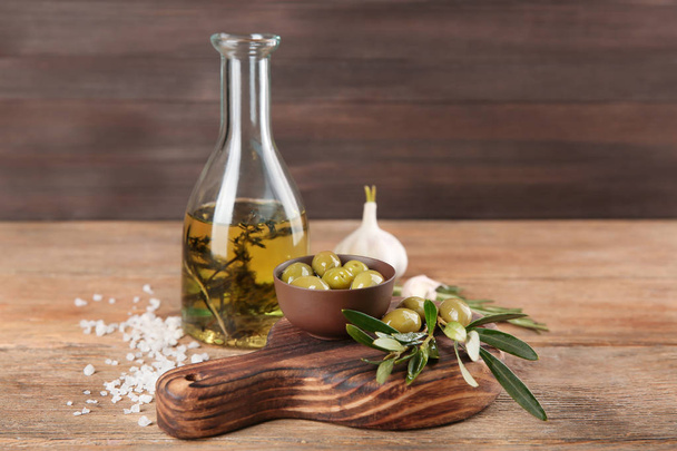 Kompozycja z konserwowane oliwki i olej na drewnianym stole - Zdjęcie, obraz
