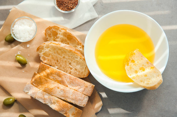 Olive oil in bowl with fresh bread on table - Zdjęcie, obraz