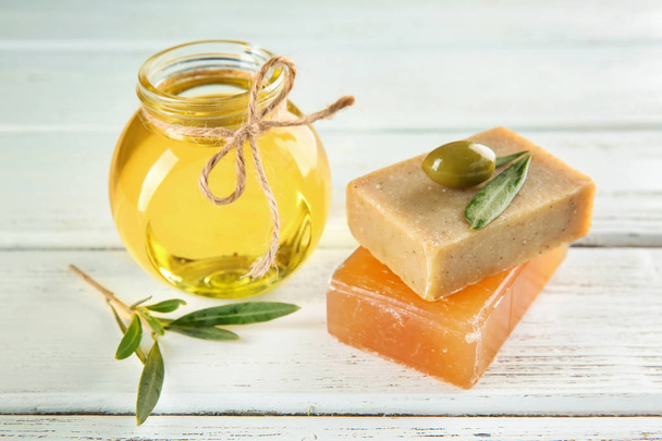 Pot à l'huile d'olive et barres de savon naturel sur table en bois
 - Photo, image