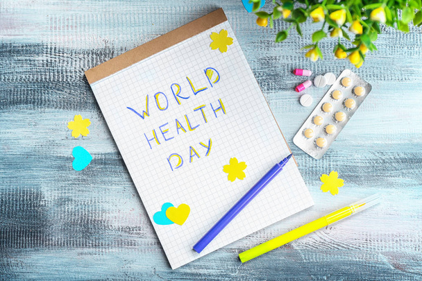 Cuaderno con palabras "Día Mundial de la Salud" y pastillas en la mesa de madera
 - Foto, imagen