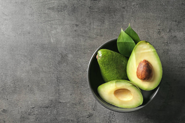 Bowl with ripe avocados on dark grey background - Foto, afbeelding