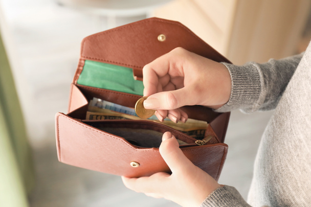 Mladá žena, uvedení mincí do peněženky uvnitř, closeup. Koncept úspory peněz - Fotografie, Obrázek