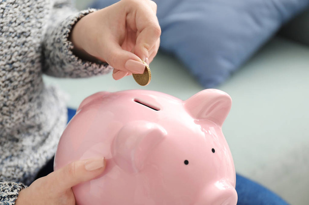 Woman putting coin into piggy bank, closeup. Money savings concept - Photo, Image
