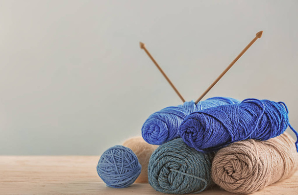 Knitting yarn with needles on table against light background - Photo, Image