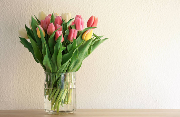 Vase with beautiful tulips on table against light background - Foto, imagen