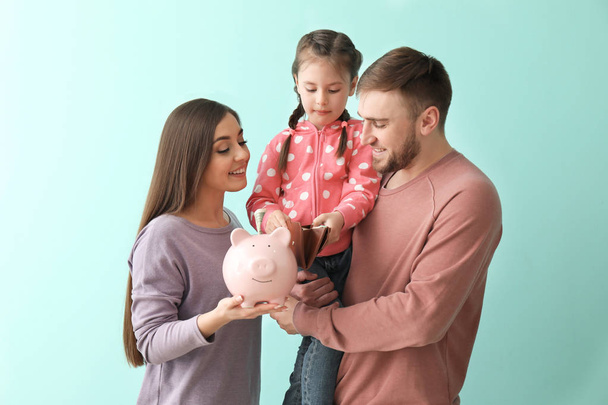 Szczęśliwa rodzina młoda Skarbonka, portfel i pieniądze na kolor tła - Zdjęcie, obraz