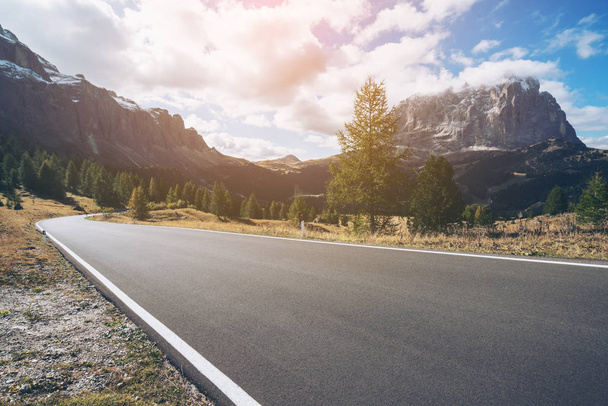 Beautiful mountain road with trees, forest and mountains in the backgrounds. Taken at state highway road in Passo Gardena, Sella mountain group of Dolomites mountain in Italy. - Photo, Image
