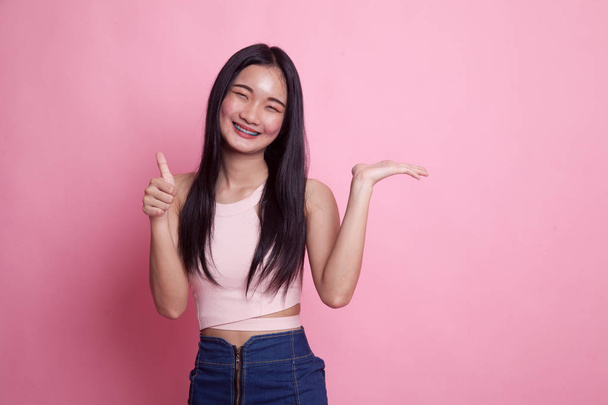 Beautiful young Asian woman show palm hand and OK sign on pink background - Photo, Image