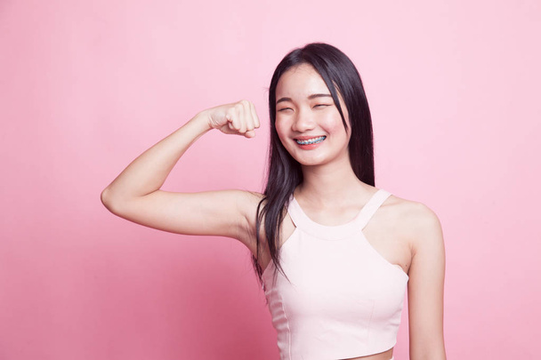 Beautiful young Asian woman flex bicep on pink background - Valokuva, kuva