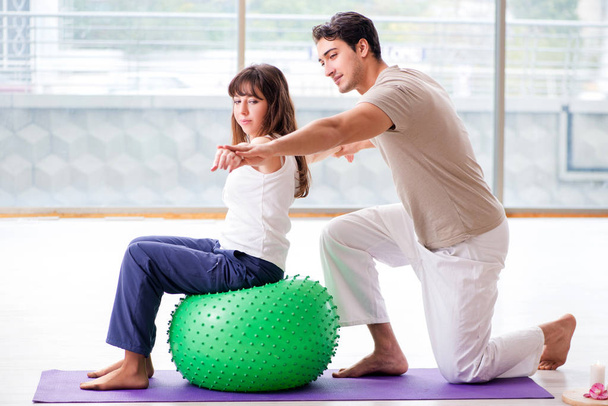 Treinador pessoal ajudando mulher no ginásio com bola de estabilidade - Foto, Imagem