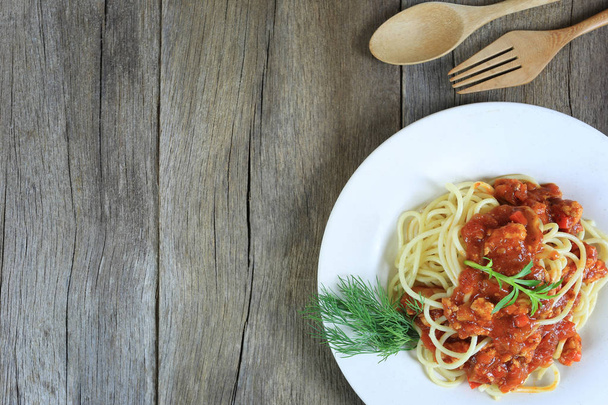 Spaghetti mit Tomatensauce in einer weißen Schüssel auf Holzboden Hintergrund und haben Kopierraum im Konzept des Essens gutes Essen ist Gesundheit. - Foto, Bild