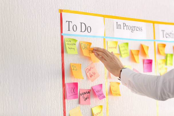 Man attaching sticky note to scrum task board in office - Photo, Image