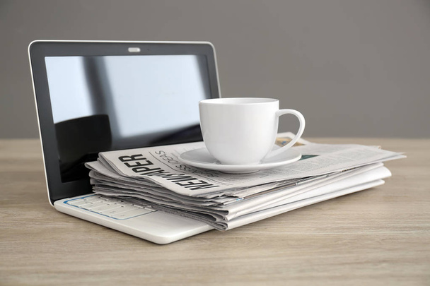 Pilha de jornais, laptop e xícara de café na mesa de madeira
 - Foto, Imagem