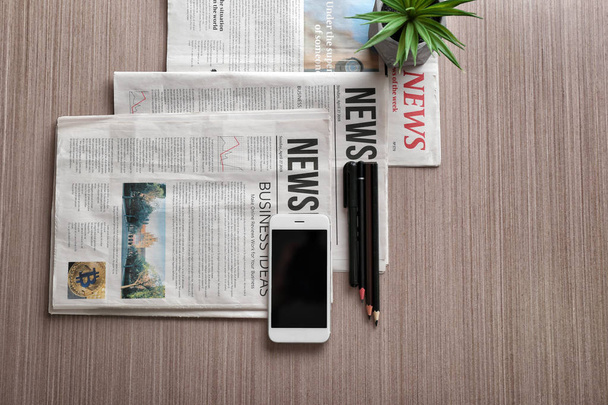 Composition with morning newspapers and phone on wooden background - Photo, Image