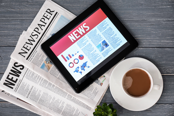 Tablet ordenador con noticias en pantalla y periódicos sobre fondo de madera
 - Foto, Imagen