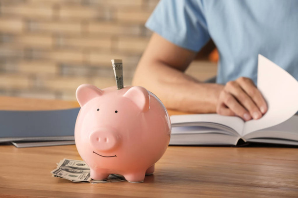 Piggy bank on table of man counting his savings - Фото, зображення