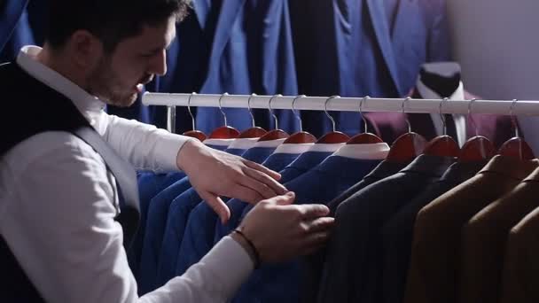 Young man choosing classical suit in the suit shop - Footage, Video