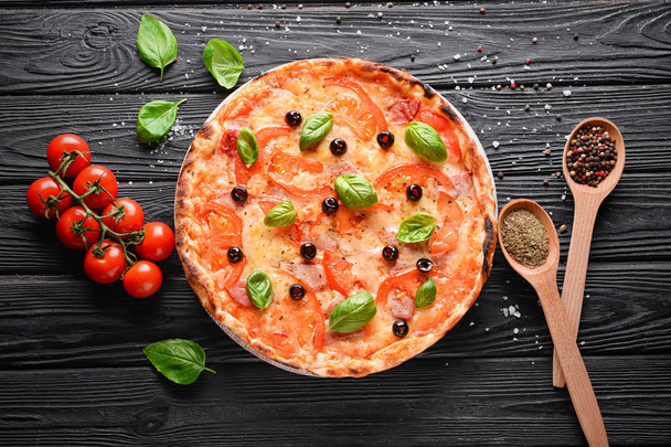 Plateau en bois avec pizza savoureuse et ingrédients sur la table
 - Photo, image